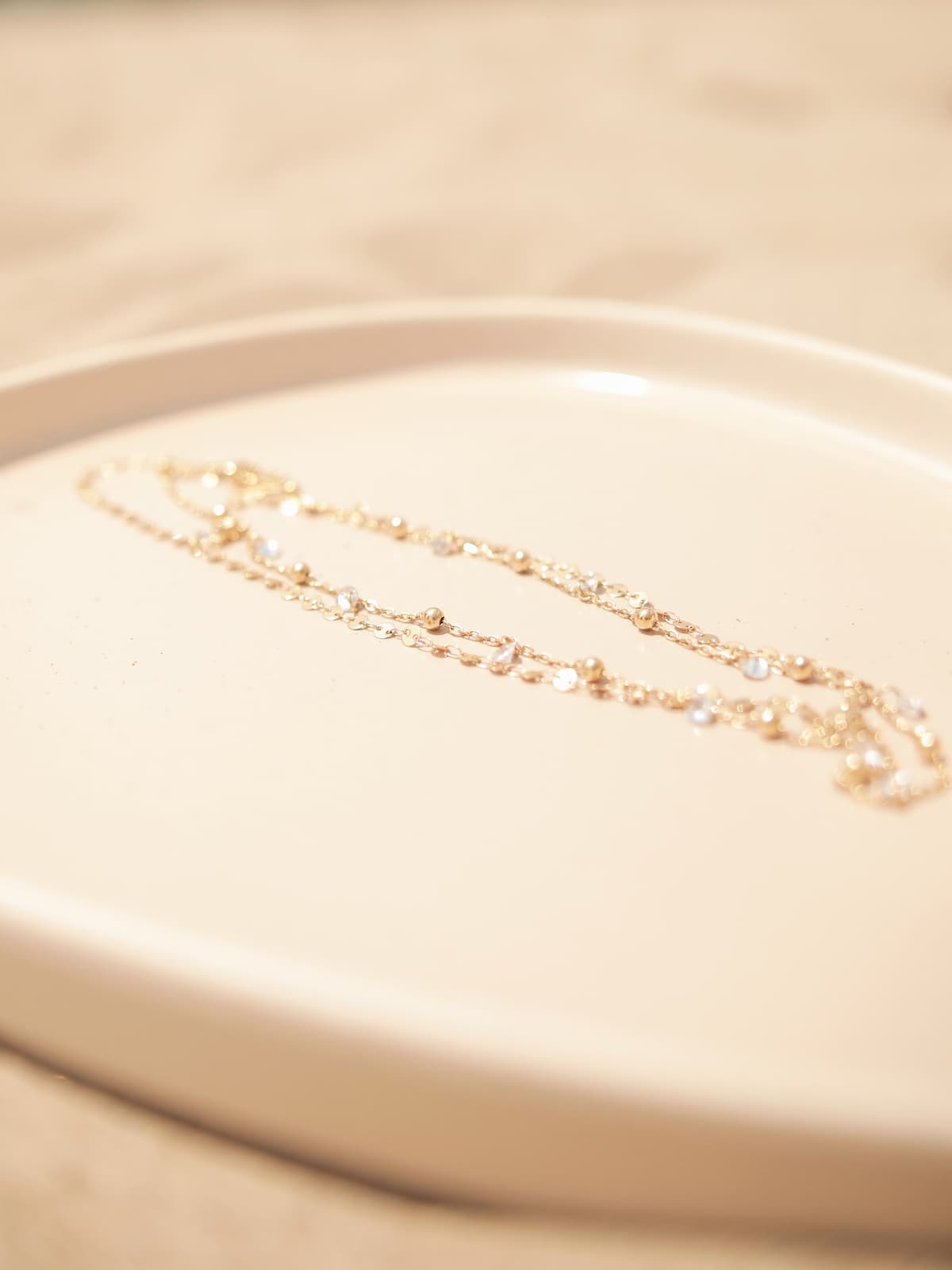 Gold Desert Flower Necklace on a beige plate