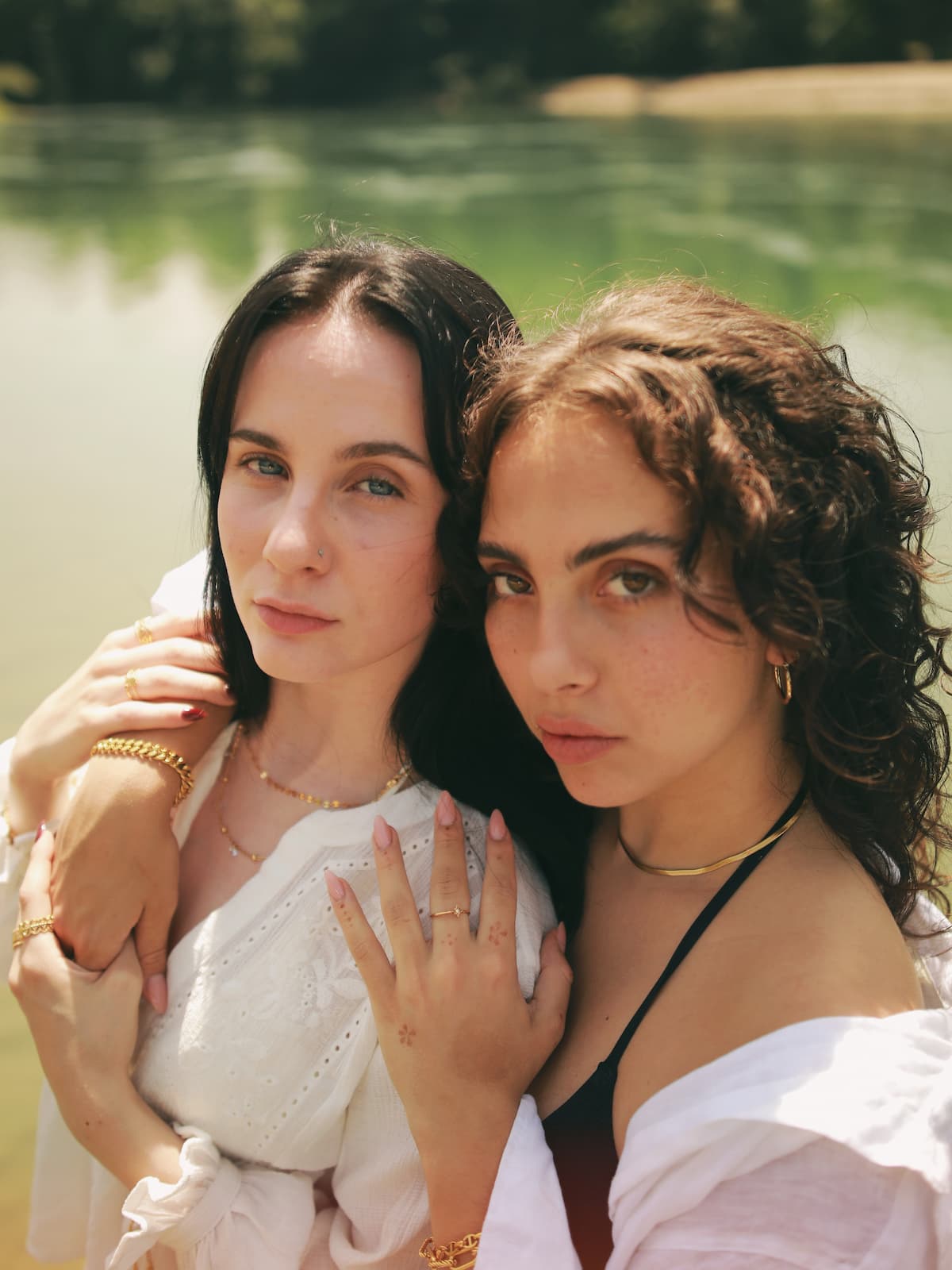 Two women standing close together by a body of water wearing the Bagatava Desert Snake Necklace