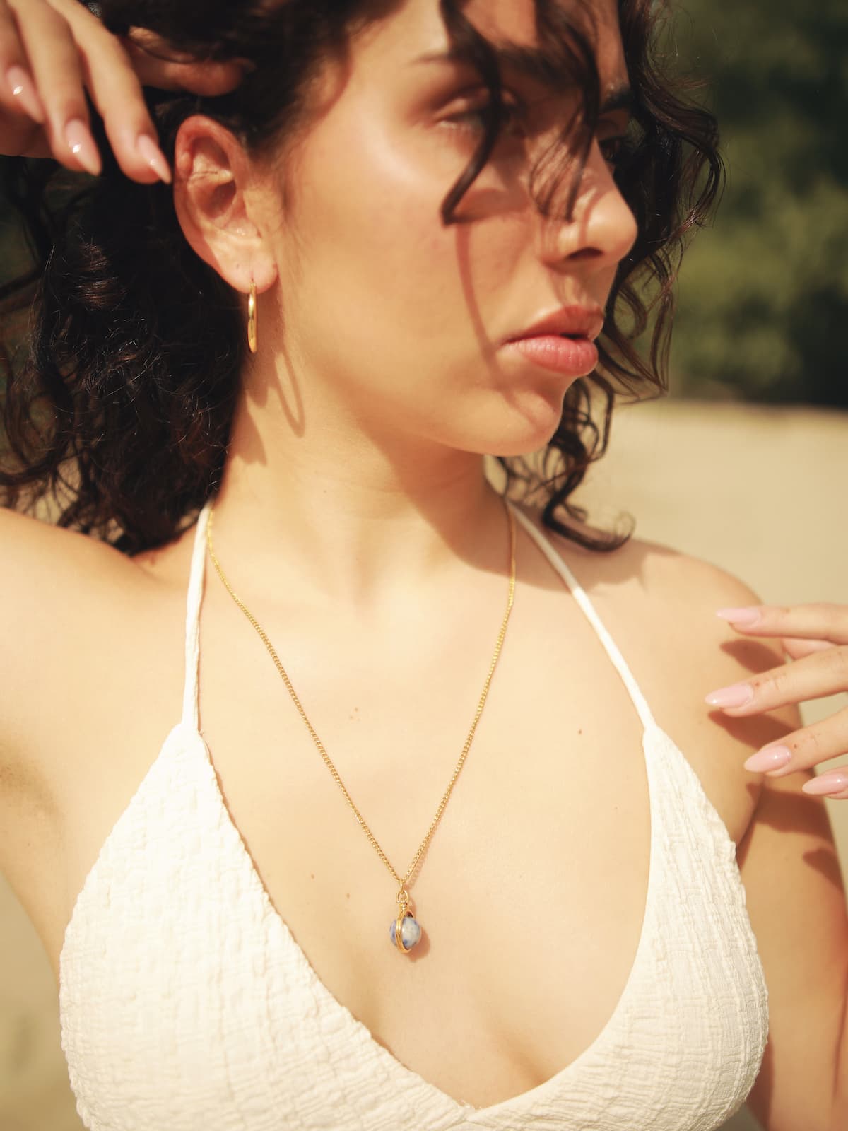 Woman wearing the gold World Necklace outdoors