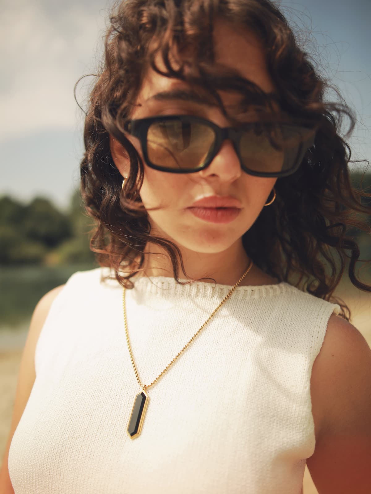 Woman wearing sunglasses and a white sleeveless top with water-resistant Onyx Necklace